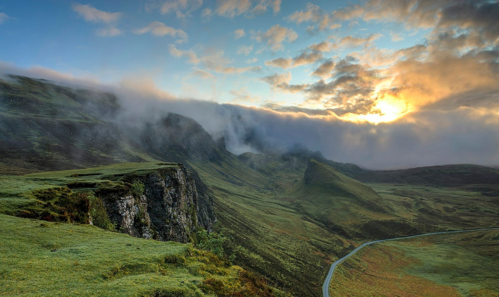 Green hills and a road under a bright sky