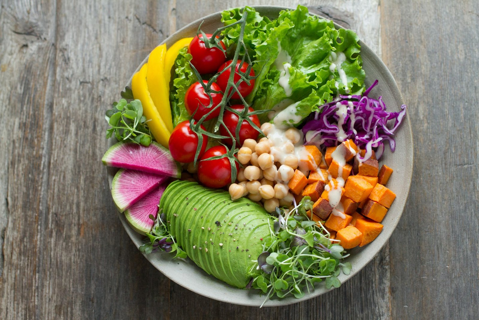A bowl of avocado, greens, tomatoes, and vegetables